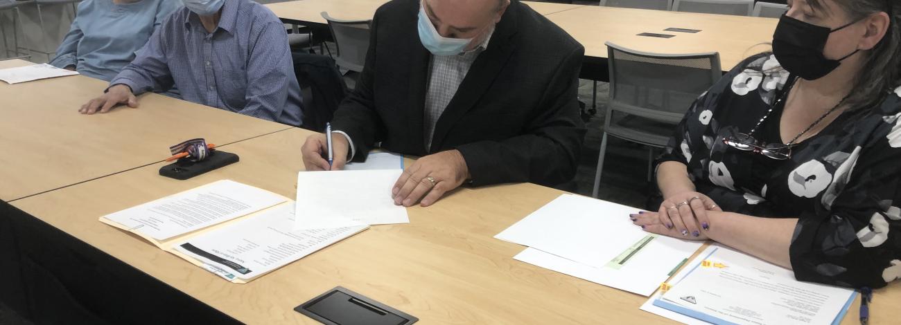 Three people sign documents at a table