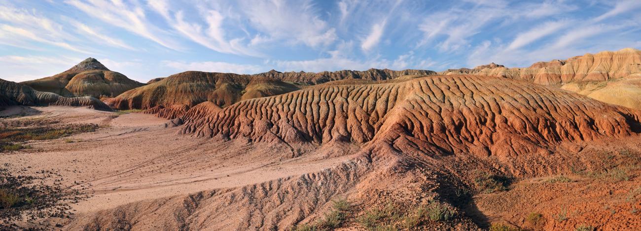 Red desert sand with wind and water erosion to soil on wispy cloudy day