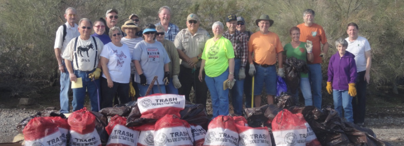 Volunteers pose for a photo with bags of trash.