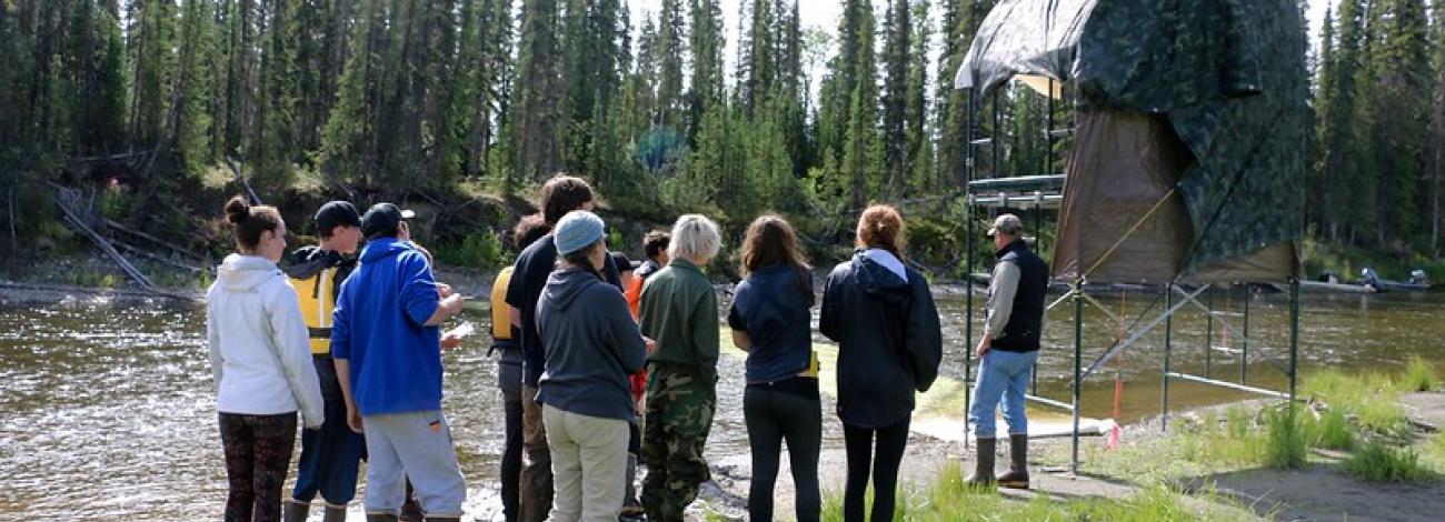 A group of people gather around a fish counting tower to learn about it.