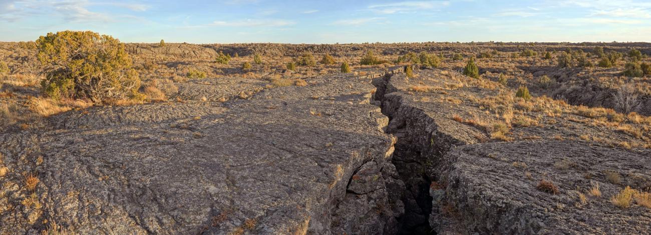 Flat rocky crevasse with shrubbery around on a clear sunny day 