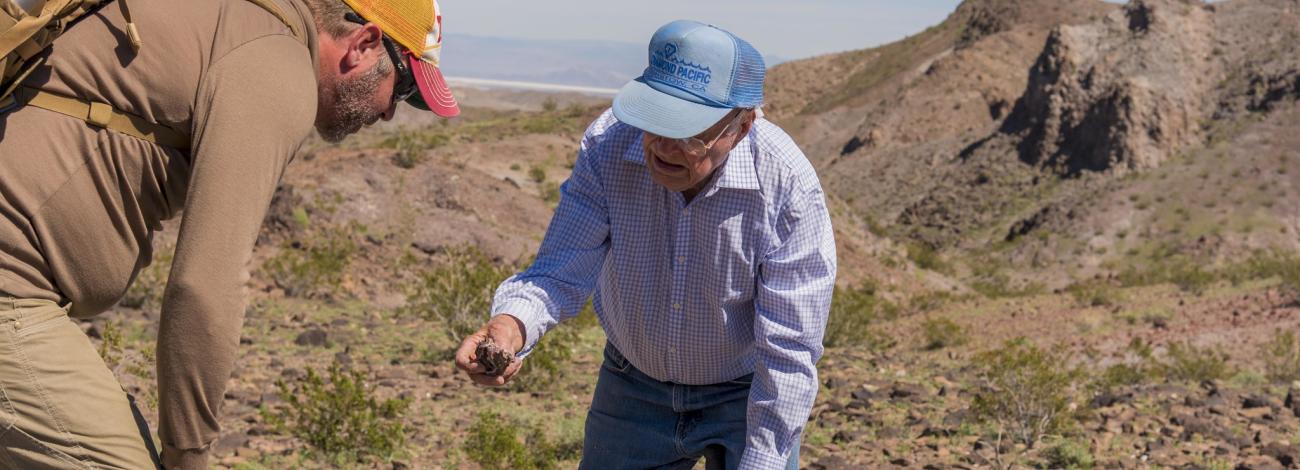 Elderly rounhounder shows a cool find to a fellow hiker in Afton Canyon in California's Mojave Trail National Monument.