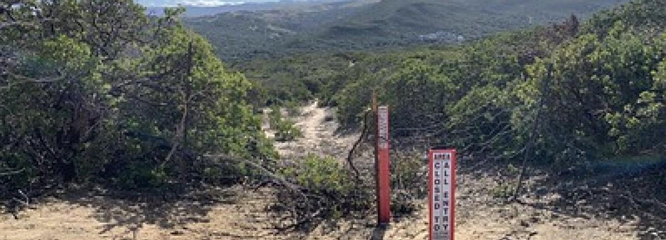 Red carsonite blocking an illegal trail through green chaparral 