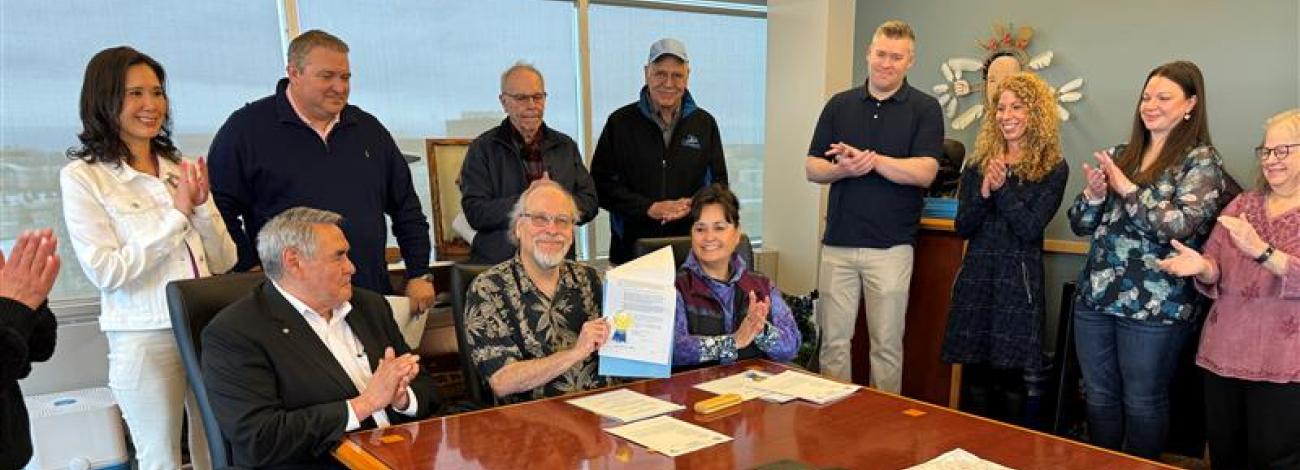 Group of people around a man holding a patent document.