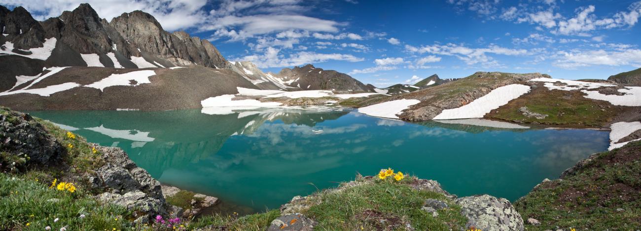 clear blue lake on clear sky day with snow capped mountain on the other side of the blue water