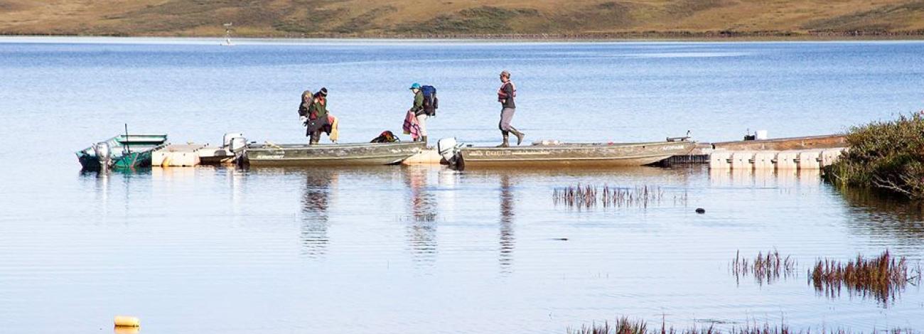 three people on the shore of Toolik Lake in Alaska