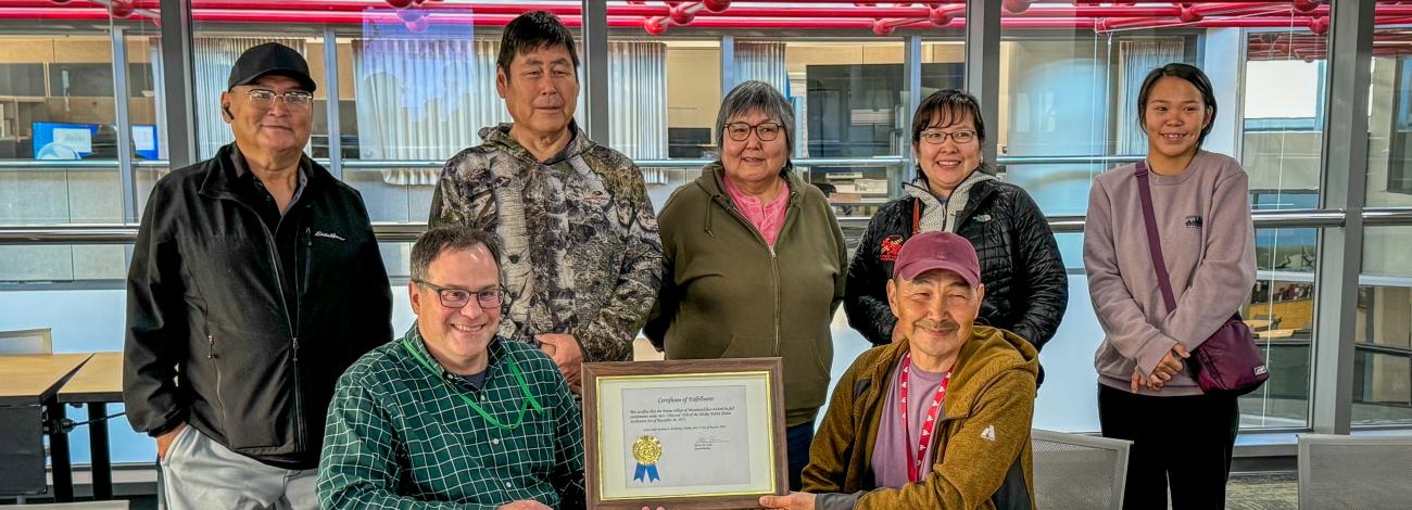 Group of people posing with ANCSA closure certificate for Manokotak Village.