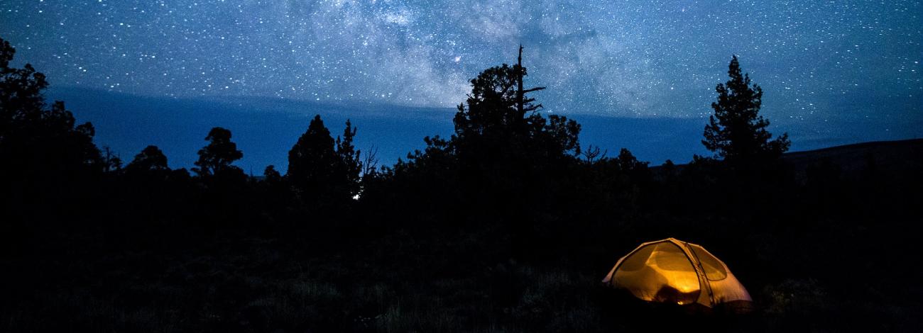 a lit up tent sits beneath a blanket of stars