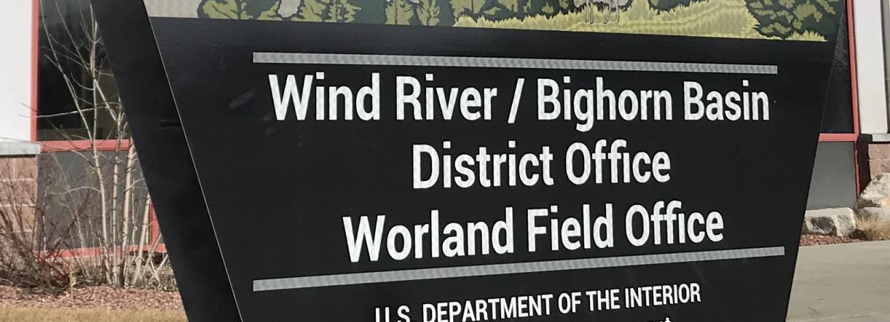A sign that reads "Wind River/Bighorn Basin District Office Worland Field Office" sits in front of a building.