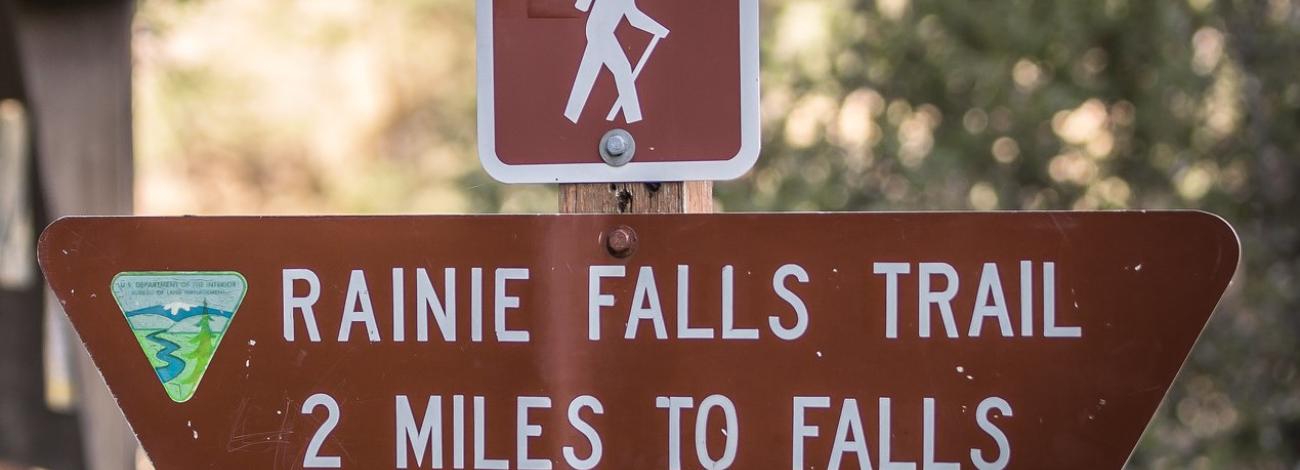 A trailhead marker that reads Rainie Falls Trail 2 Miles to Falls. 