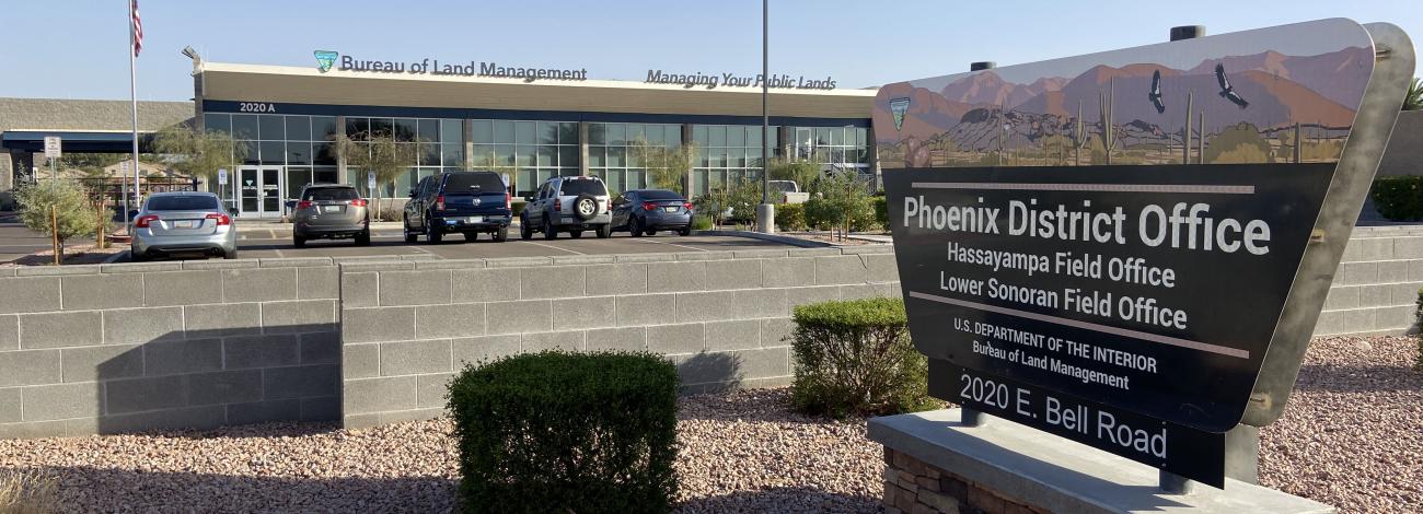 a view of an office building with a sign that reads Phoenix District Office, Hassayampa Field Office, Lower Sonoran Field Office, U.S. Department of the Interior, Bureau of Land Management