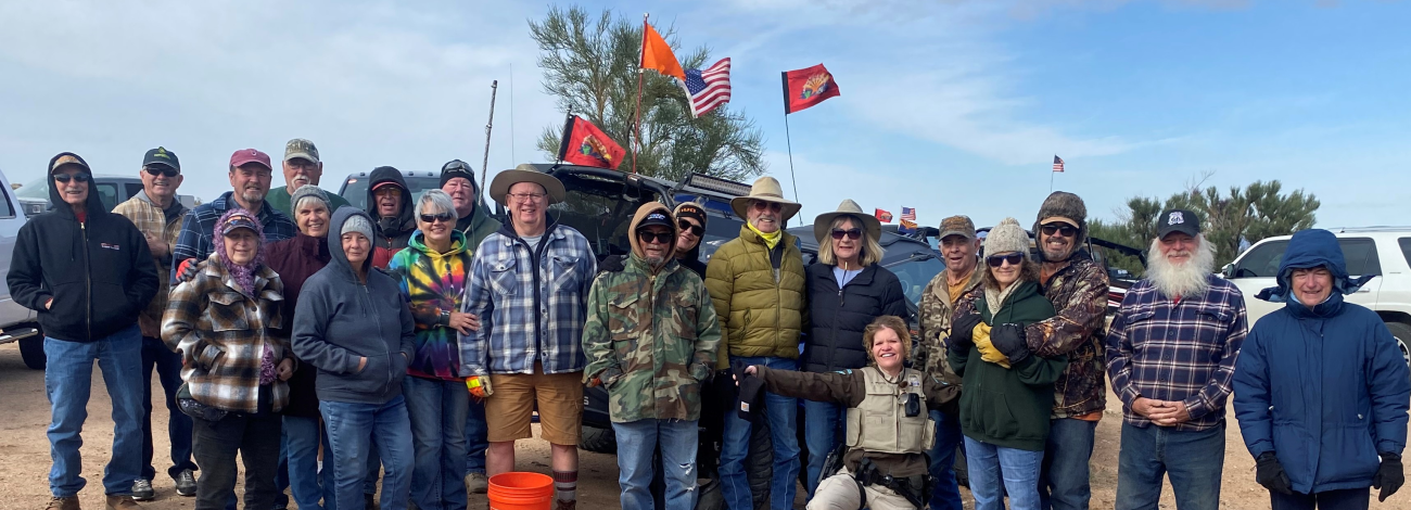 Volunteers pose in front of off-road vehicle