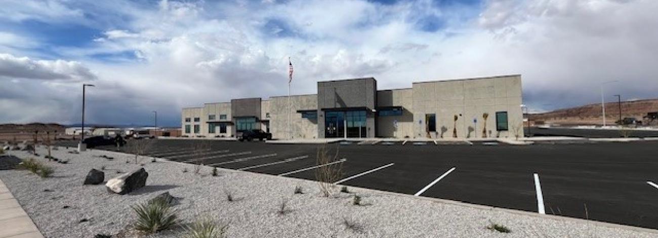 A new building with a parking lot and rockscaped parking strip under a blue sky.
