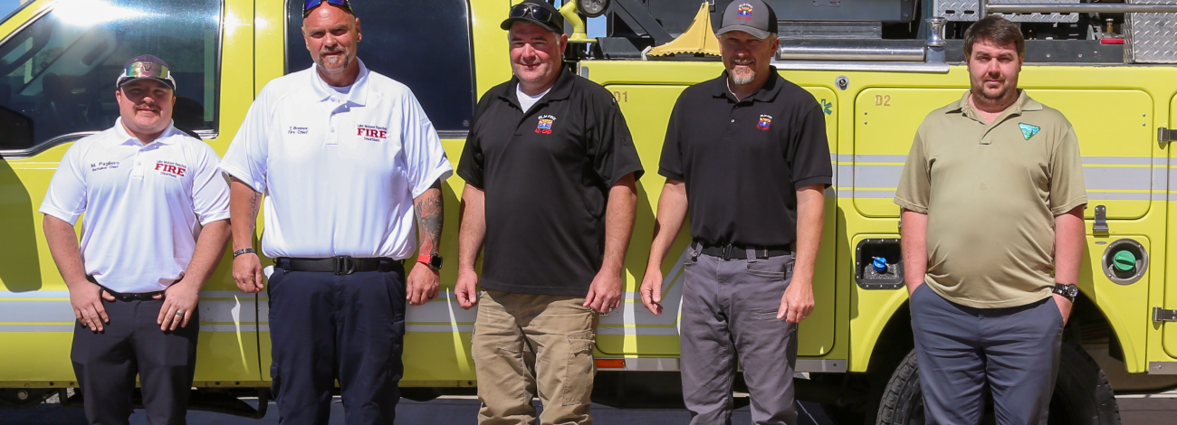 Five men stand in front a type 6 fire engine during transfer ceremony.