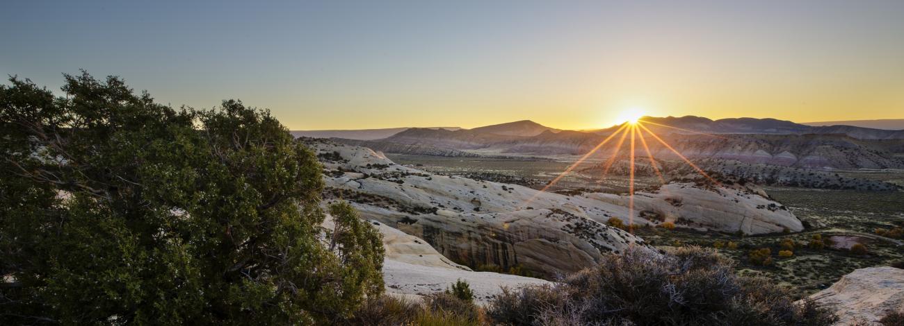Sun sets over a mountain range in the distance.