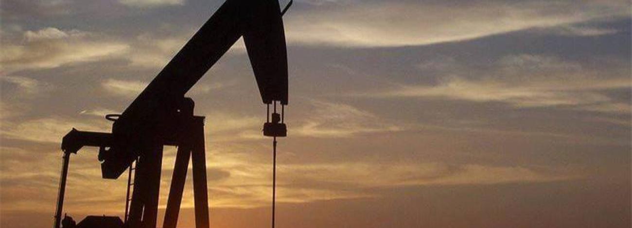 Silhouette of an oil and gas pump jack at sunset