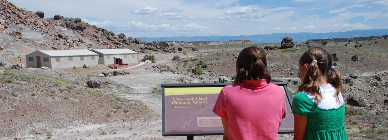Kids looking at interpretive sign overlooking Cleveland Lloyd Dinosaur Quarry