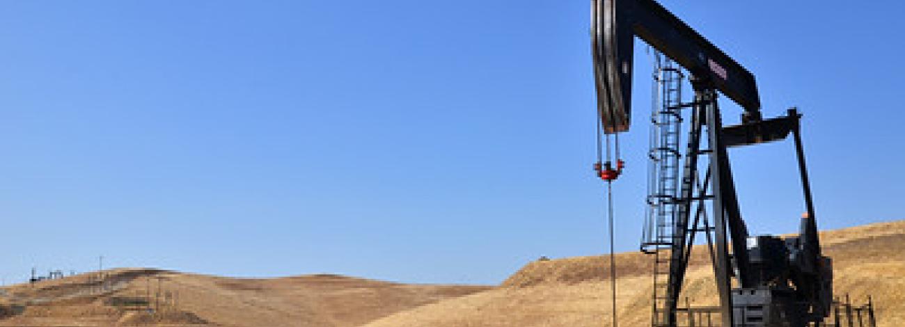 An pump jack in rolling grass fields.
