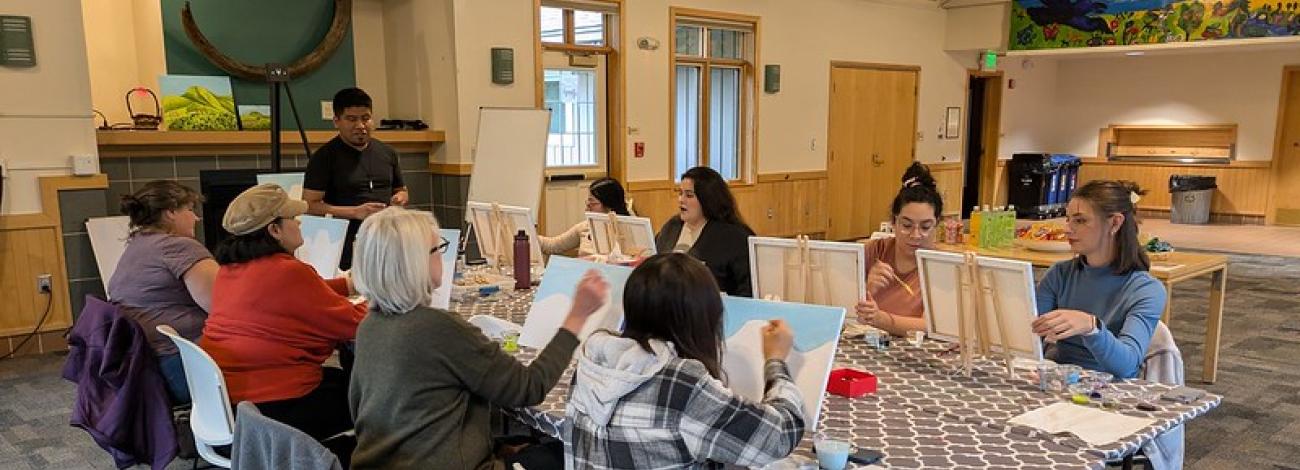 Adults paint on canvasses during an art workshop