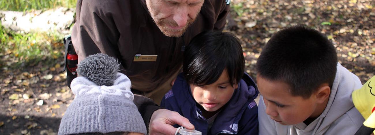 Educator looking through a magnifying glass with children