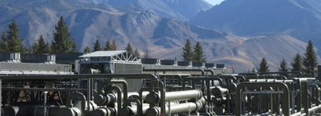 A geothermal plant in front of large mountains. 