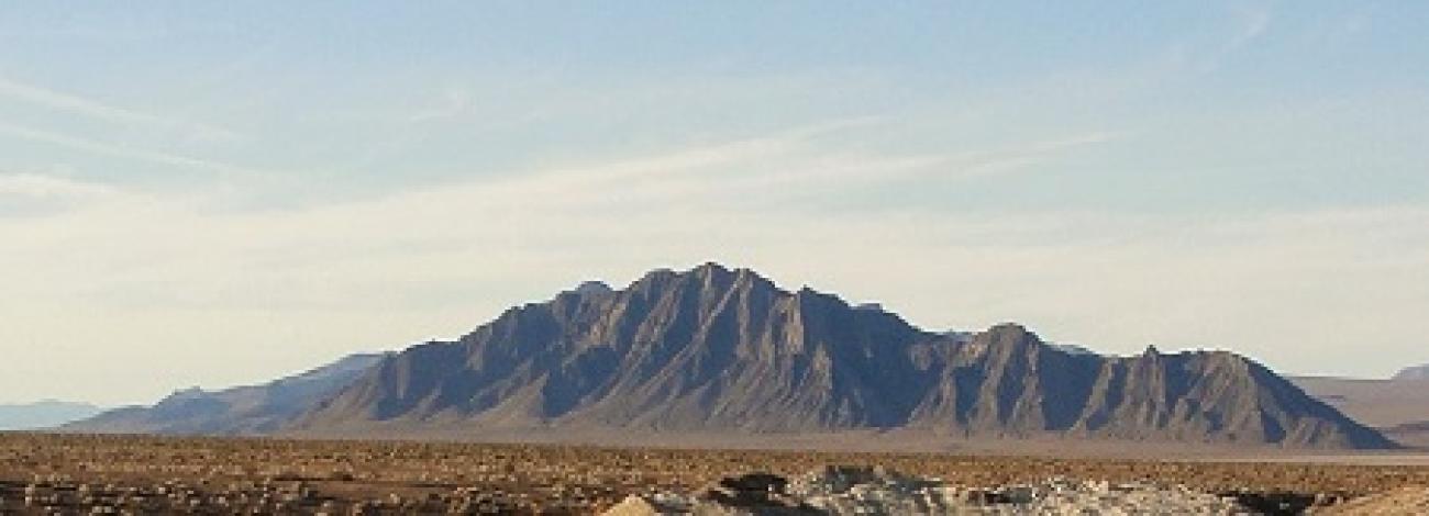 A small mountain range rises from a desert floor.
