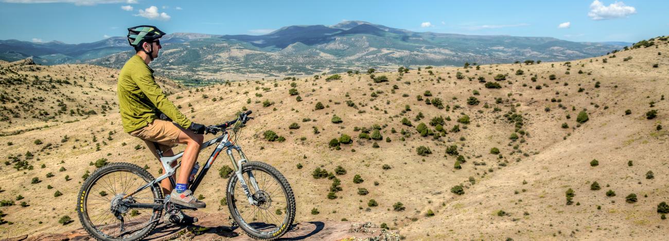 The San Luis Valley lays out in front of a mountain biker as he peers down from an elevated position.