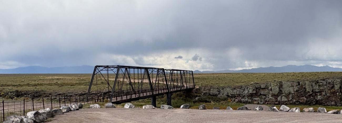 gravel parking lot with view of the historic lobatos bridge which is a metal bridge