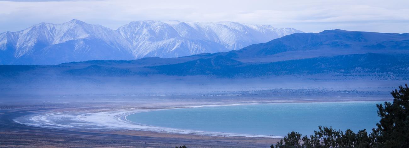 wintery day with a lake and mountain in the distance. bluish feeling and colors