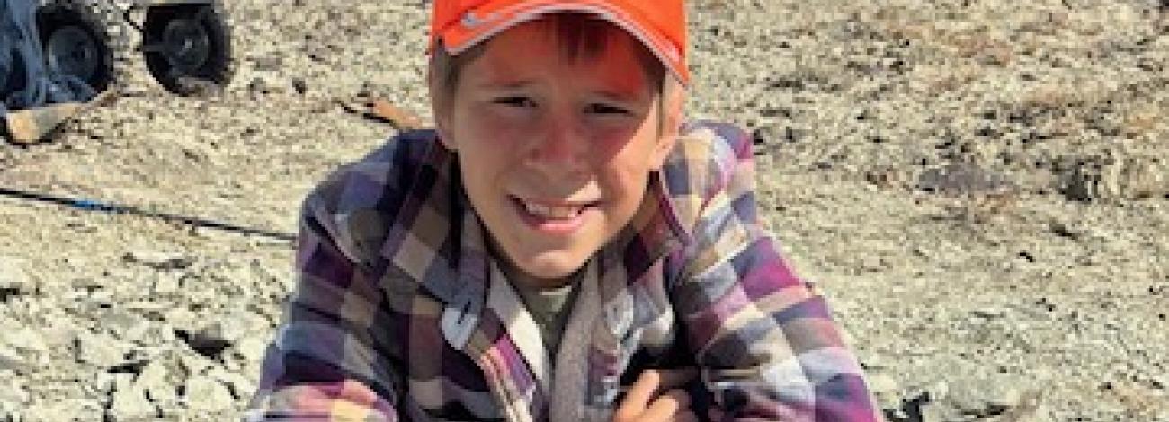 Touren Pope poses for a photo with the fossilized turtle he discovered on BLM with a blue sky