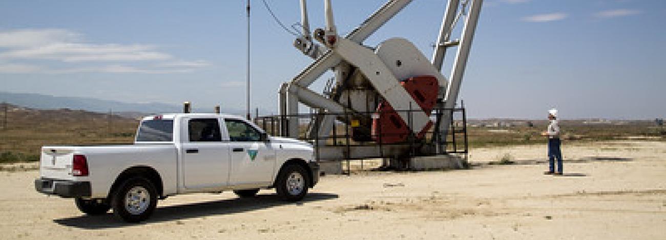 An inspector walks around a pump jack.