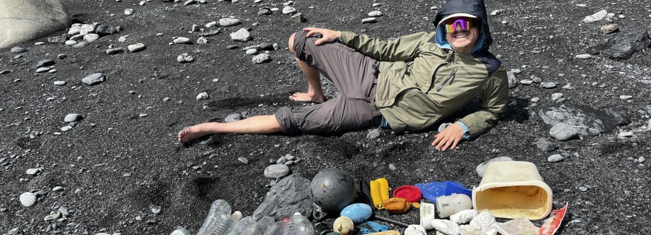 Hiker poses with trash haul on the black sands of the lost coast.