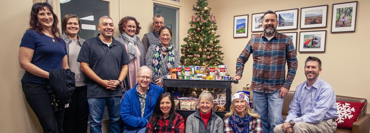 group of staff surround a cart of donated food during the holidays.