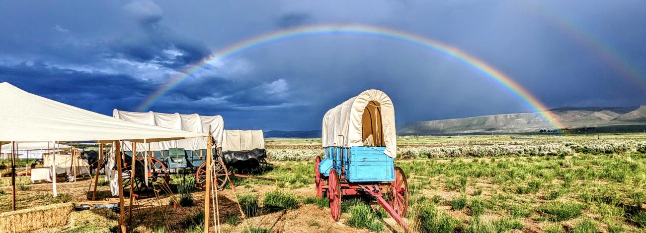 Rainbow arches over covered wagon in bright sun