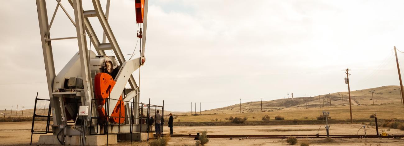 an oil derrick on a barren dusty ground.