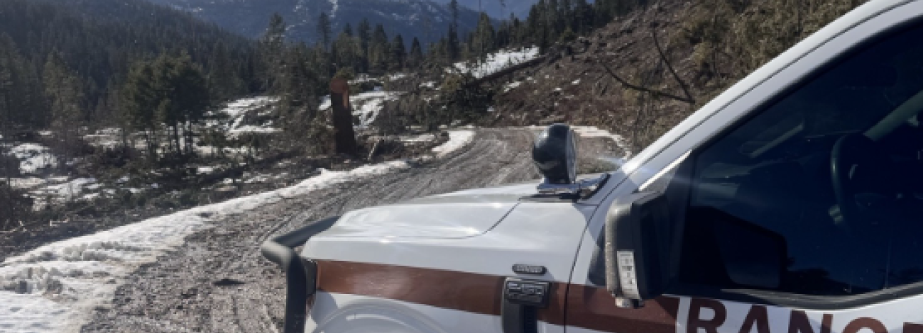 A photo of the front of a law enforcement vehicle on a dirt road with a scenic landscape in the background
