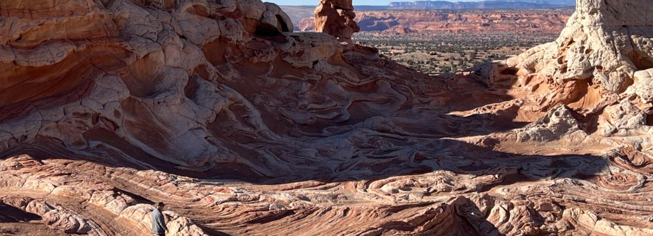 Swirling red and white sandstone formations under a clear blue sky in a desert landscape.