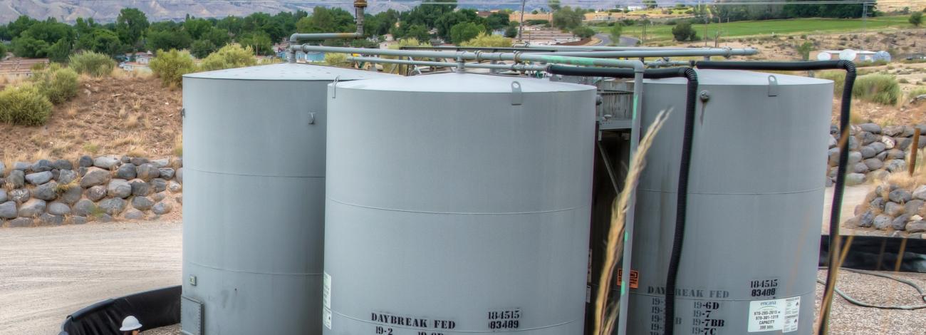 A technician stands beside a BLM Colorado oil and gas well pad.