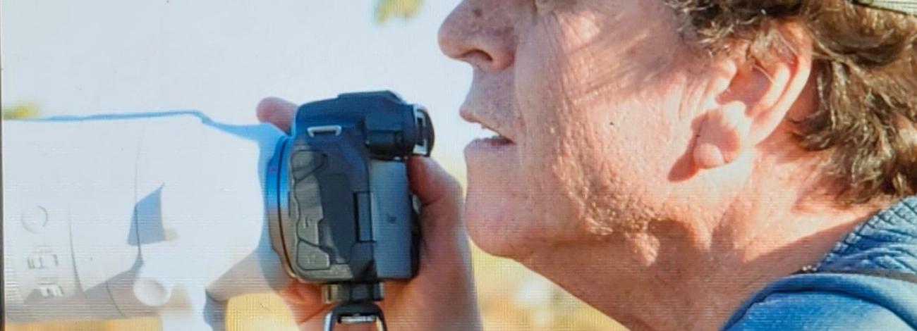 A man wearing a baseball cap holds a camera
