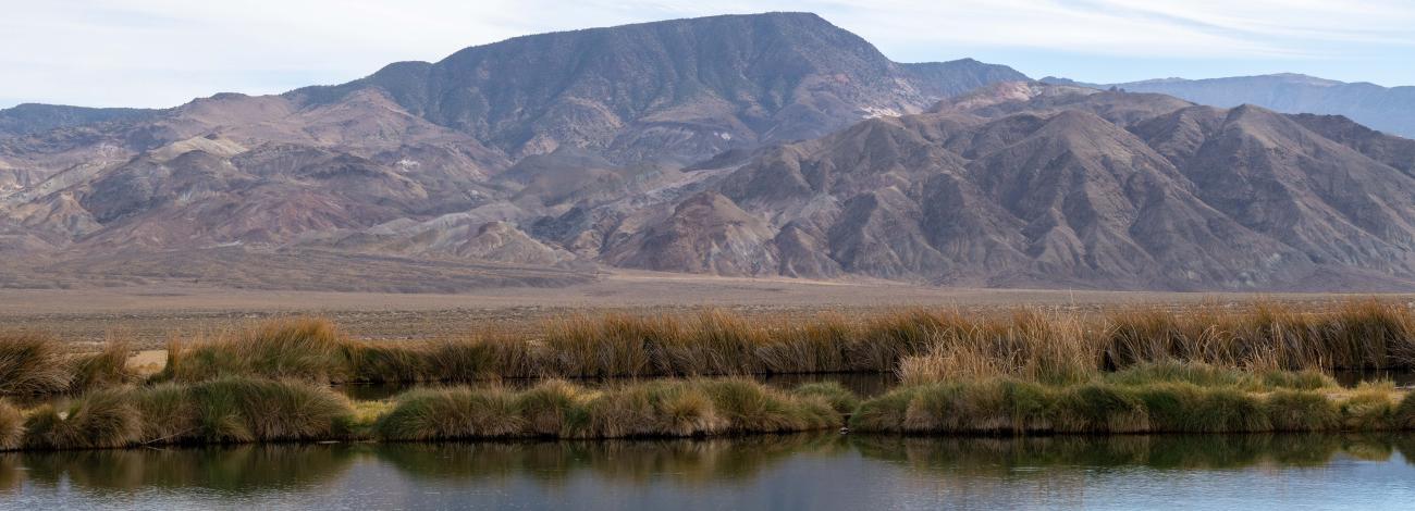 White clouds over a mountain with a pond reflecting the natural beauty that abounds throughout the Battle Mountain in District.