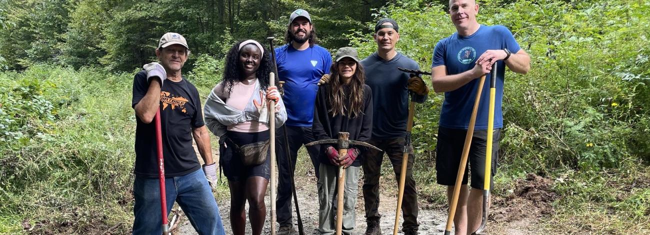 People standing with shovels and tools on a dirt path