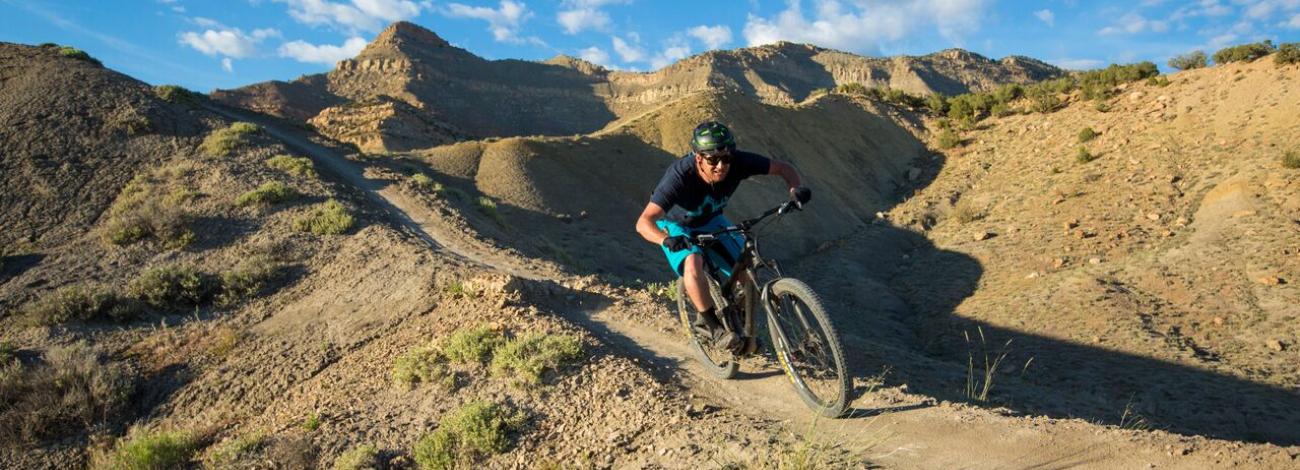 Mountain biker riding on the dirt 18 Road and Kokopelli Loops Trails in Colorado.