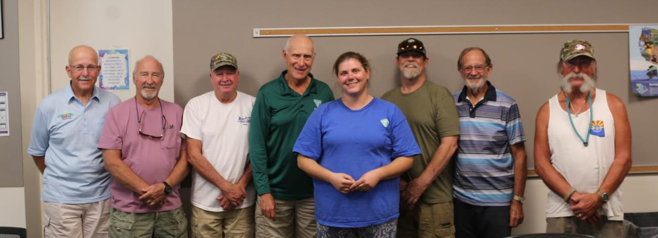 Seven fisheries volunteers stand together with the program leader in a meeting room during a volunteer appreciation event.