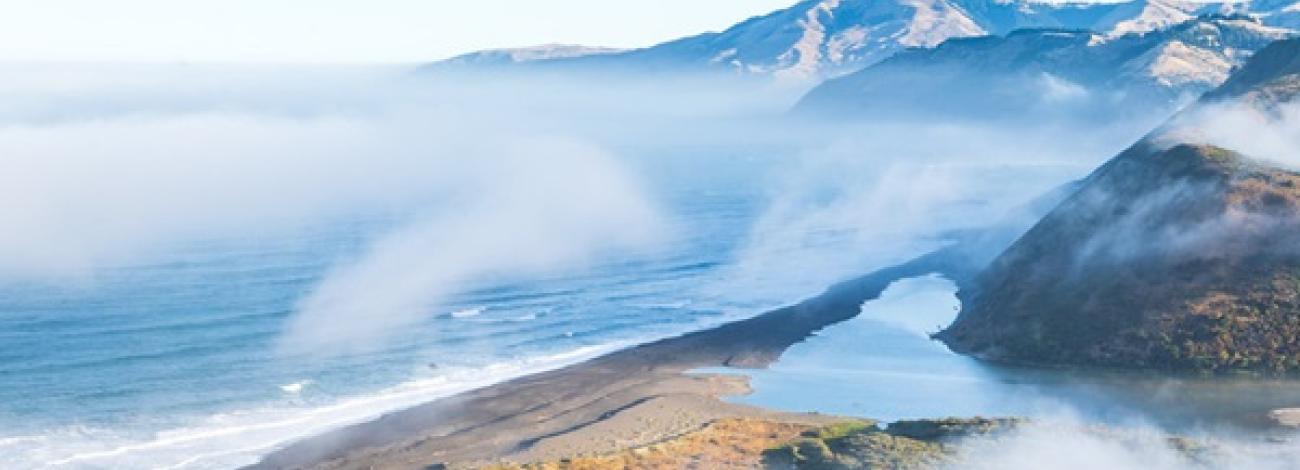 Fog descends on a mountainous beach.