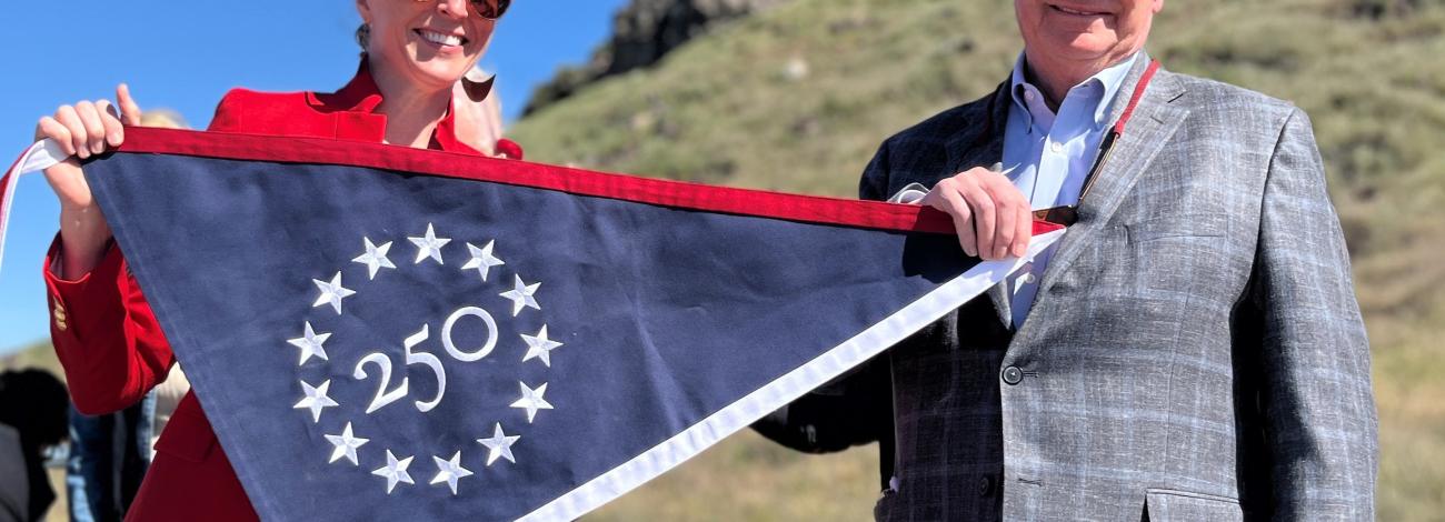 Image of two people holding a commemorative America 250 anniversary banner