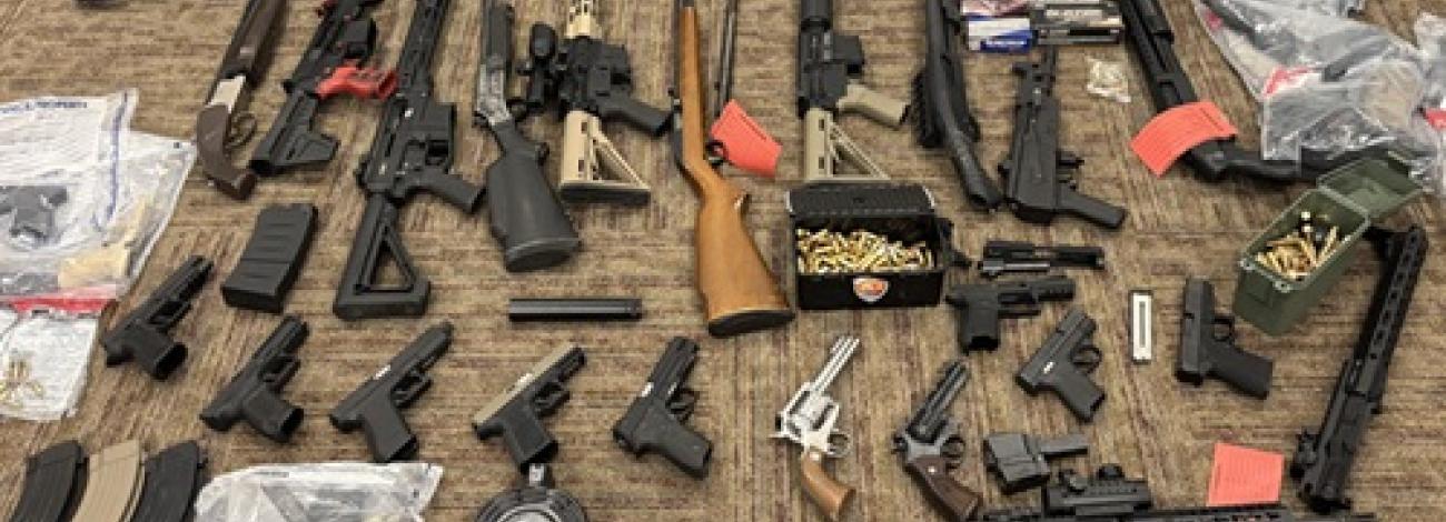 A collections of seized rifles and hand guns.