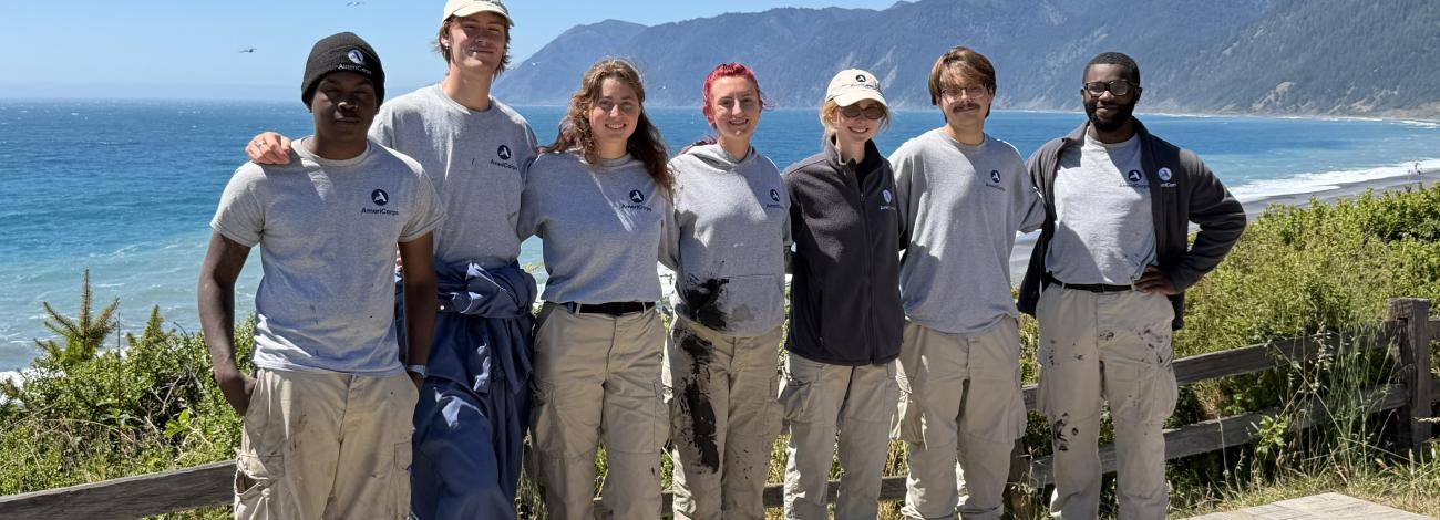 A line of volunteers posing in front of the Pacific Ocean.