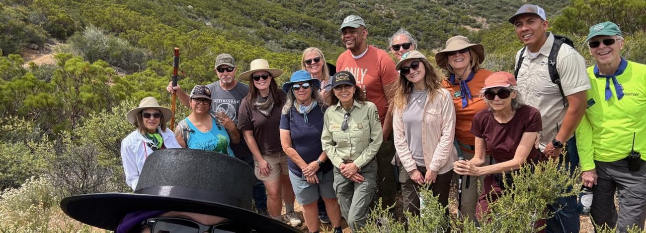 A group of people in outdoor gear in a brush covered hill.
