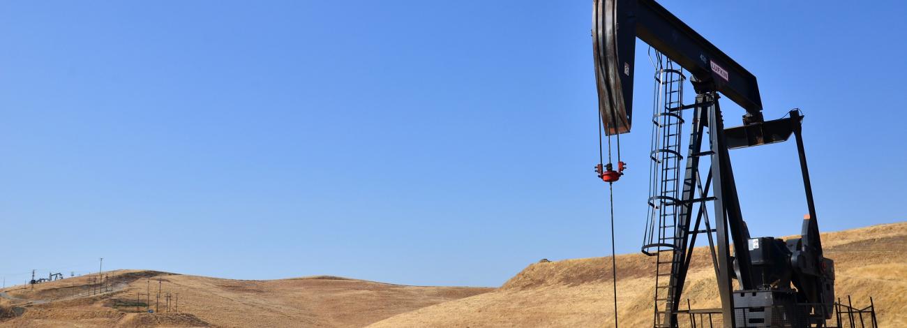An oil derrick in a dry grassy hill