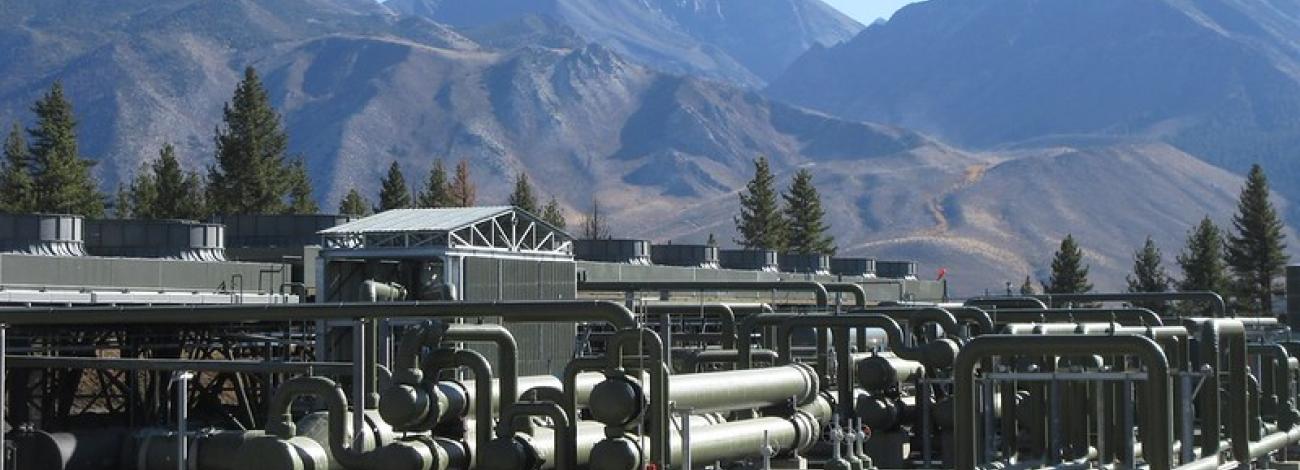 A geothermal plant with large mountains in the background.